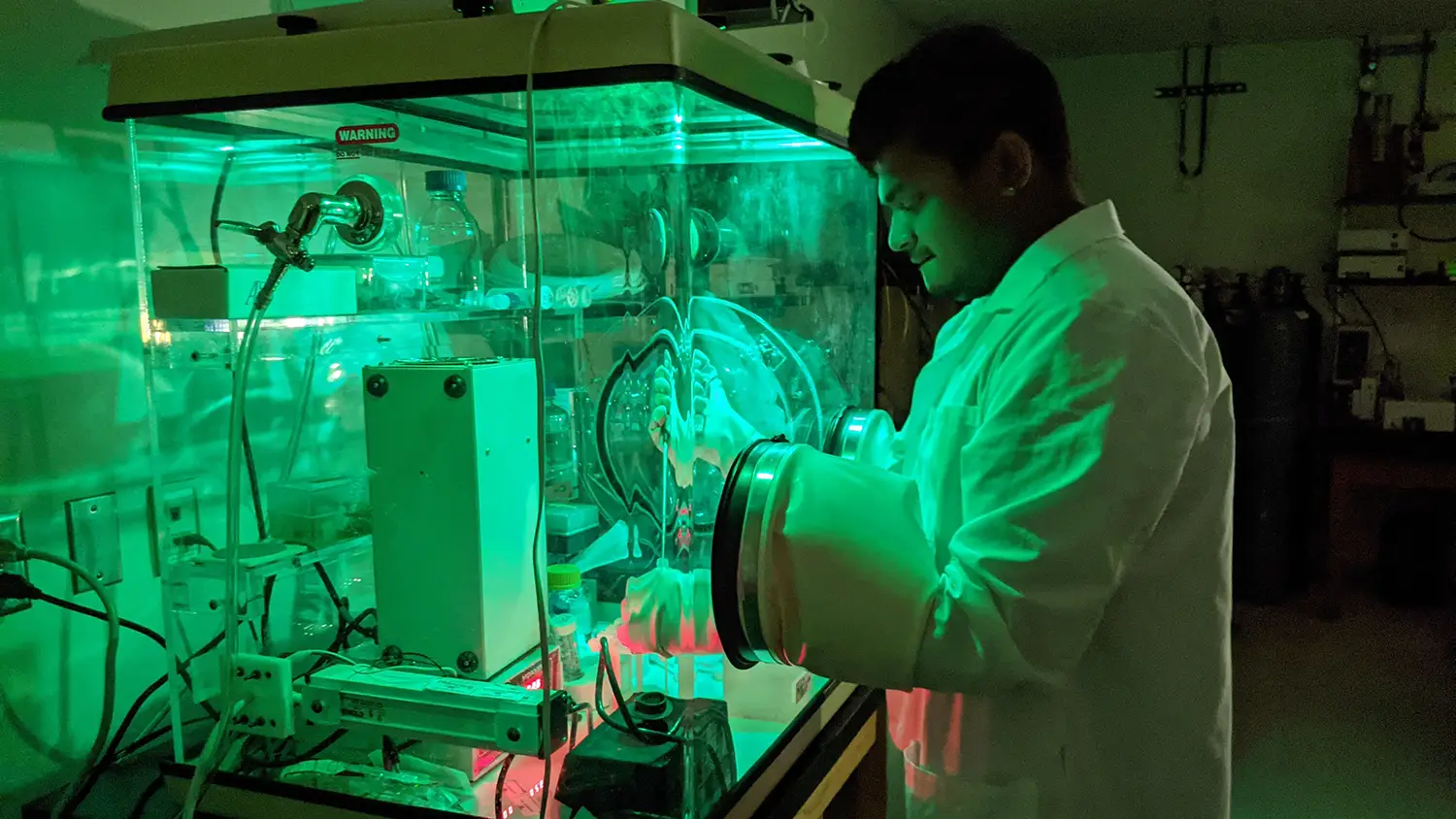 Green-hued photo of a researcher working with lab equipment